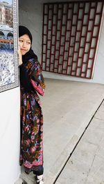 Woman looking away while standing against wall