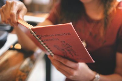 Midsection of woman reading book at cafe