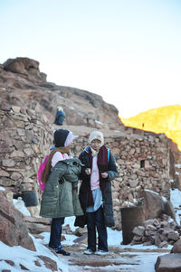 People photographing on rock against clear sky