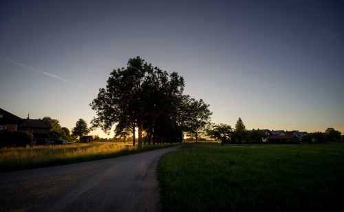 Road amidst field against clear sky