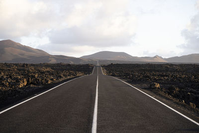 Road leading towards mountain range against sky in lanzarote