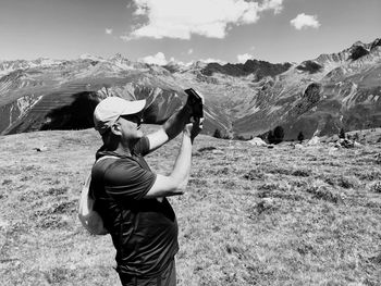 Rear view of man standing on mountain against sky