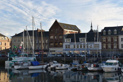 Boats moored at harbor against buildings in city