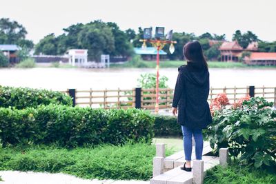 Rear view of woman standing against plants