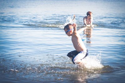 Full length of shirtless boy playing in sea