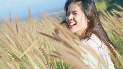 Portrait of young woman standing on field against sky