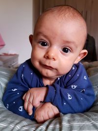 Portrait of cute baby boy on bed at home