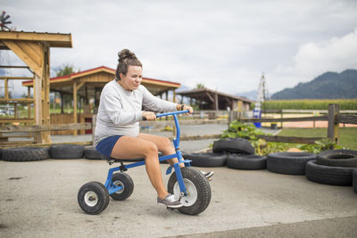 Fun expectant mother riding oversized tricycle on race track.