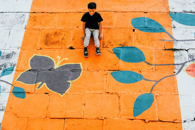 Low angle view of man climbing on graffiti wall