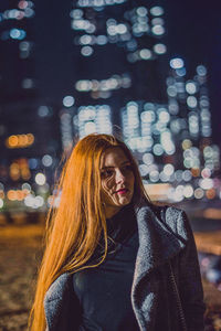 Portrait of young woman in illuminated city at night