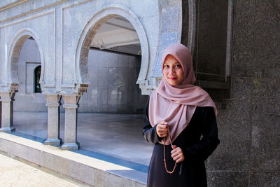 Portrait of woman standing against wall