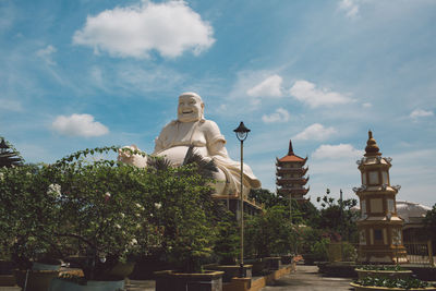 Low angle view of statue by buildings against sky