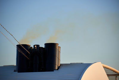 Low angle view of smoke emitting from chimney against sky