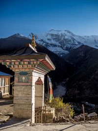 Traditional building by mountains against clear sky