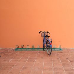 Bicycle parked against orange wall