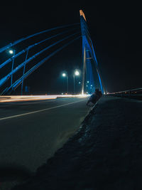 Light trails on bridge against sky at night