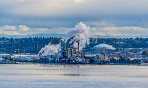 Steam rises from a factory with the tacoma dome nearby.