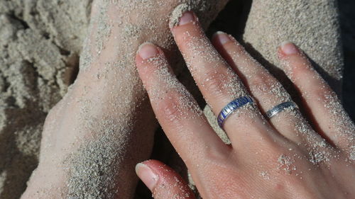 High angle view of hands on woman at beach