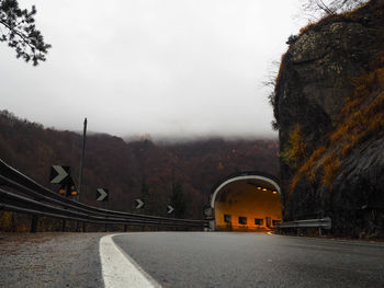 Empty road leading towards tunnel against sky
