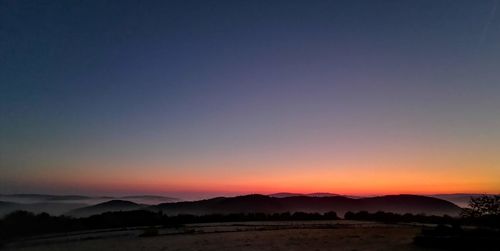 Scenic view of silhouette mountains against clear sky during sunset