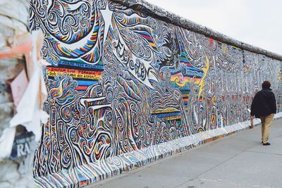 Rear view of woman walking on multi colored wall