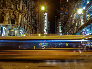 Light trails on street amidst buildings in city at night