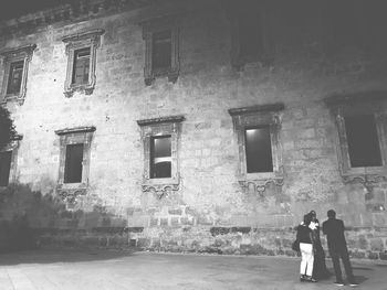 Rear view of people walking on old building