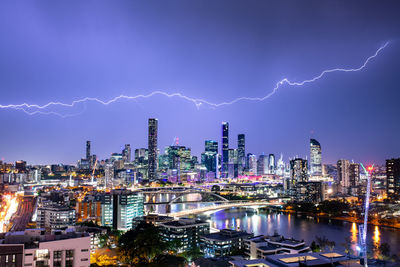 Lightning over illuminated buildings in city at night