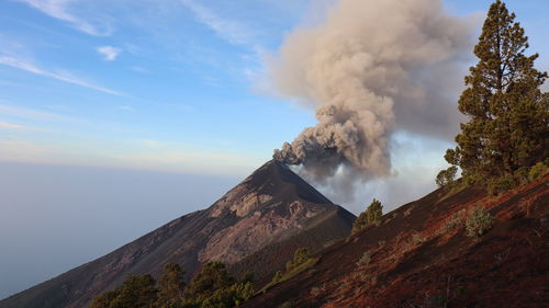 Scenic view of smoking volcano against sky