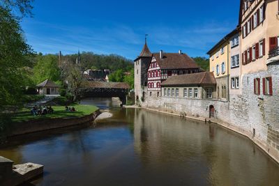 Bridge over river by buildings in city against sky