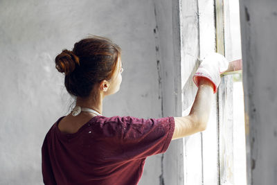 Rear view of woman standing against wall