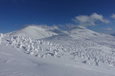 Scenic view of snow covered mountains against blue sky