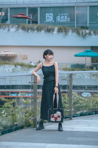 Portrait of young woman standing by railing