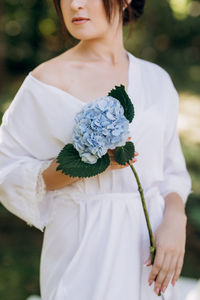 Midsection of woman holding white flower