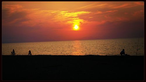 Silhouette of people on beach at sunset