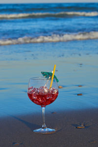 Red wine glass in water at beach