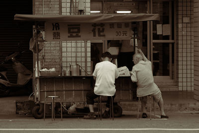 Rear view of men sitting at market stall