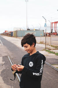 Teenage girl looking at camera while standing against sky