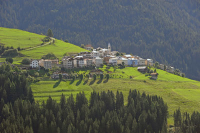 Scenic view of agricultural field by houses and mountains against sky