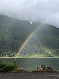 Scenic view of mountains against sky with multiple rainbows.