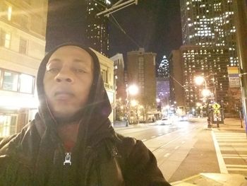 Portrait of young man on city street at night