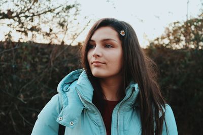 Portrait of beautiful young woman standing against tree