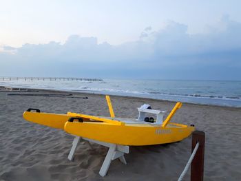 Yellow airplane on beach against sky