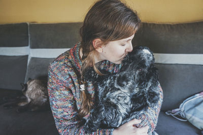 Woman kissing dog at home