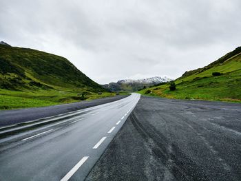 Empty road by mountains against sky