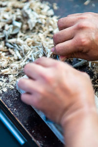 Wood shavings carpenter working with a metal spokeshave and a blurry background.