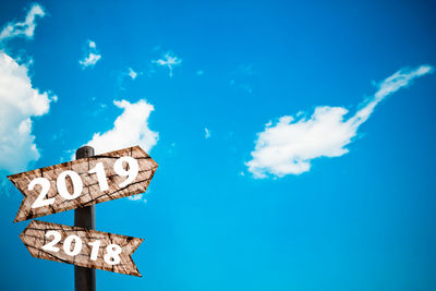 Low angle view of sign against blue sky