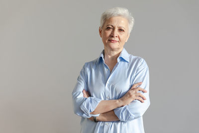 Portrait of young woman standing against gray background