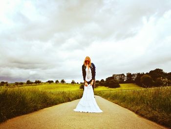 Woman standing of footpath amidst field