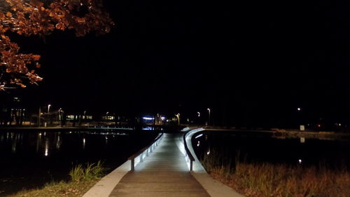 Illuminated walkway against sky at night